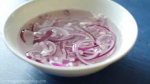 Mix water with white vinegar in the bowl. Add onion slices in a bowl and marinate for 15 min.