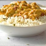 Peanut butter chicken served with a bowl of rice, with scallions and chili flakes on top.