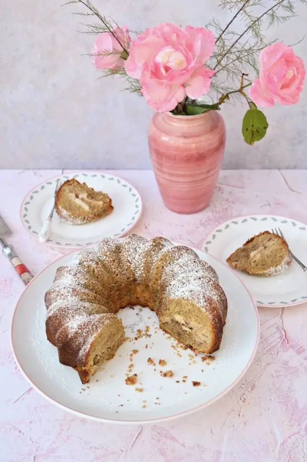 Irish apple bundt cake sliced and served on white plates with rose flowers on the table