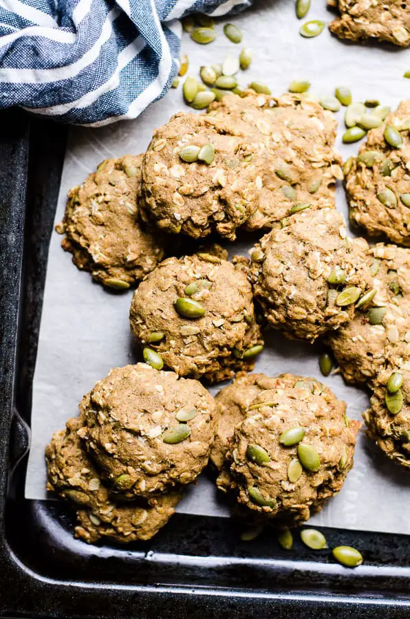 Pumpkin cookies with pumpkin seeds in a baking tray with white parchment paper