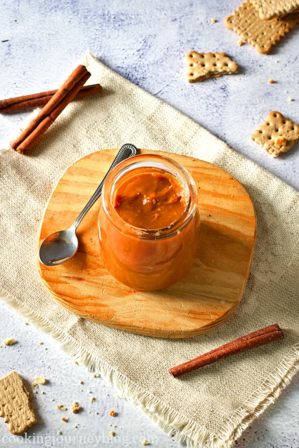 Cajeta caramel sauce served with a spoon and cinnamon sticks, served in the jar on the wooden board