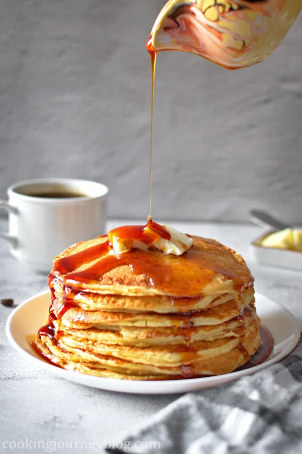 Pouring syrup on fluffy buttermilk pancakes.
