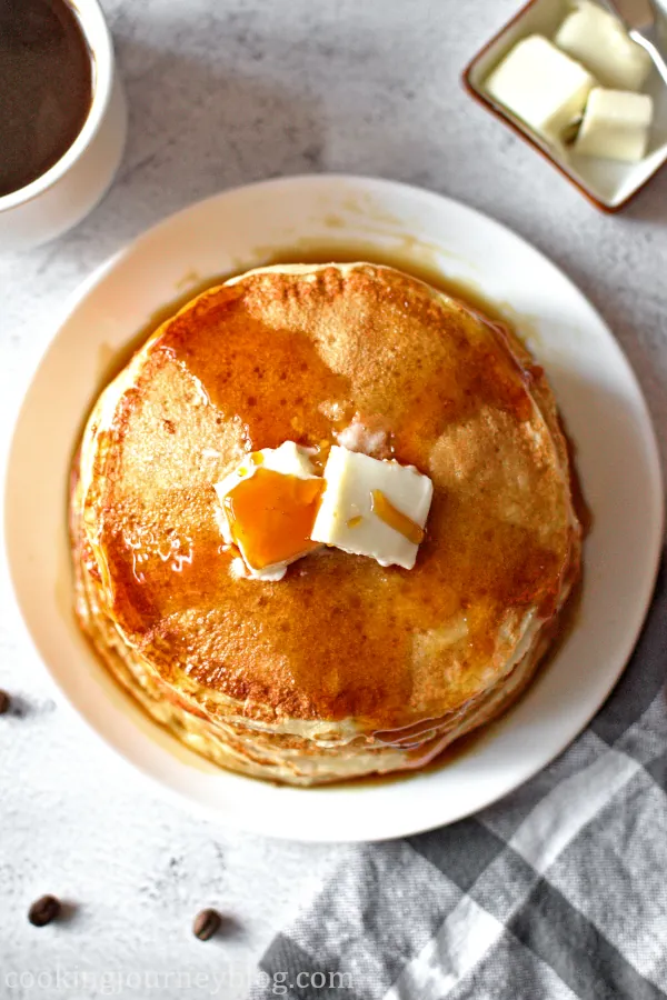 Fluffy buttermilk pancakes served on the white plate with butter.