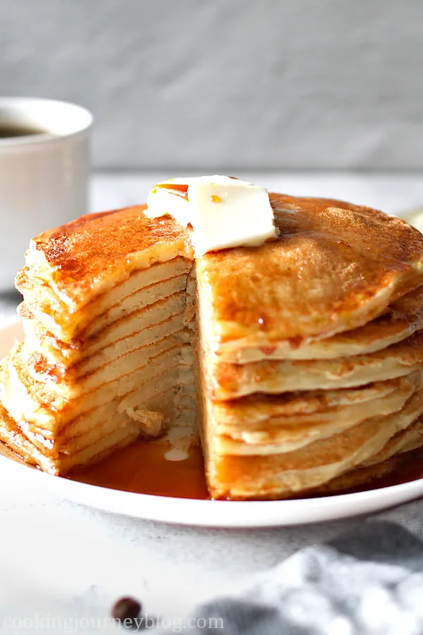 A stack of buttermilk pancakes, cut with a knife.