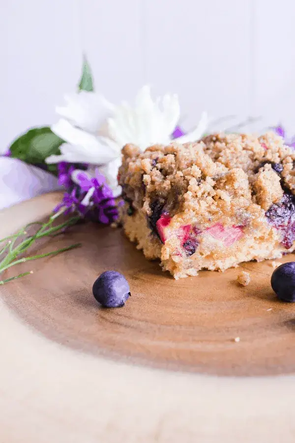 Blueberry Rhubarb Buckle with Cardamom Streusel served on a board with flowers