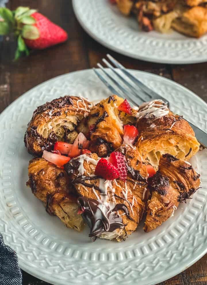 French toast served on a white plate with chocolate and strawberries