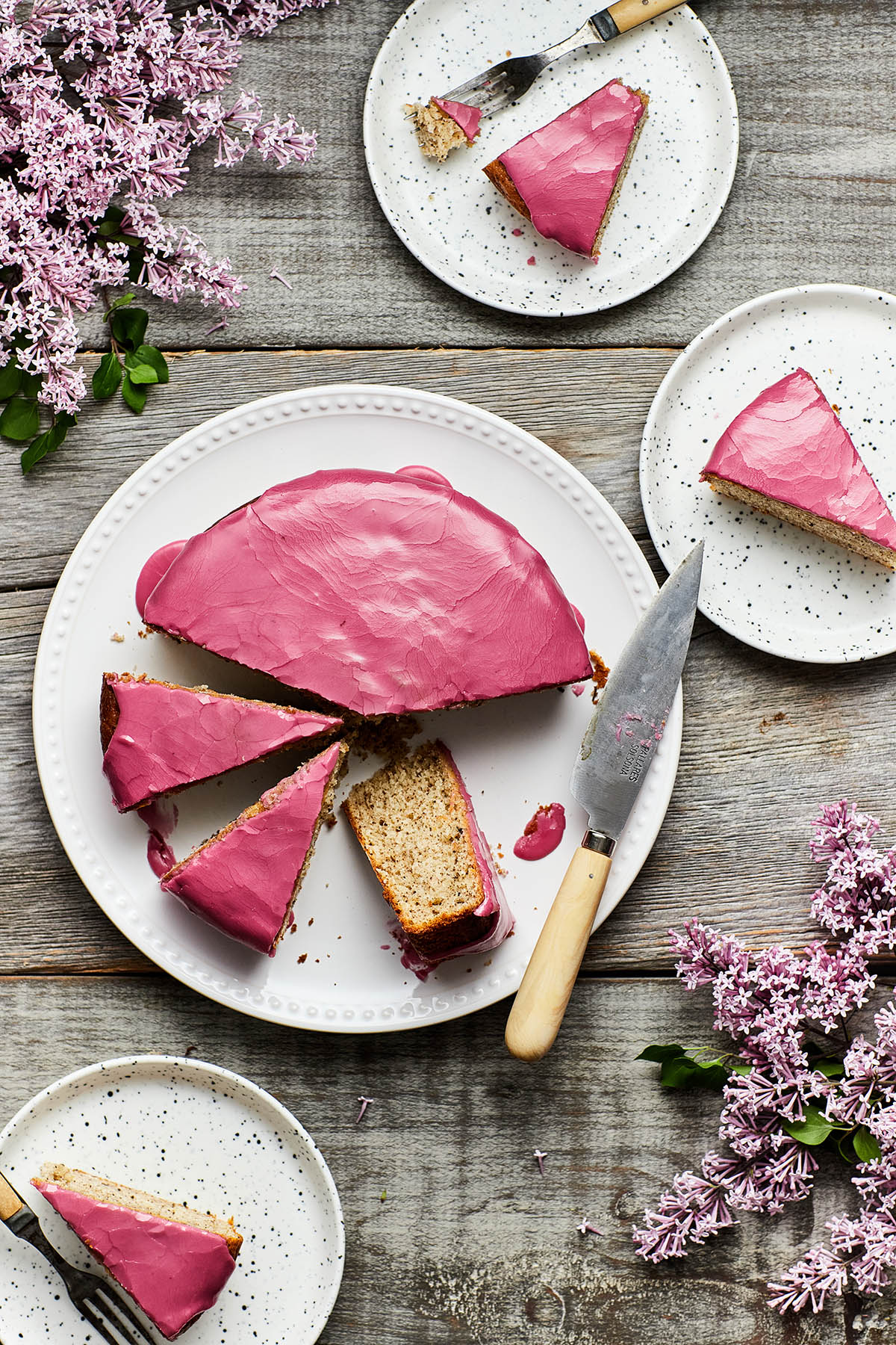 Pink glaze ona cace, served sliced on a white plate with knife
