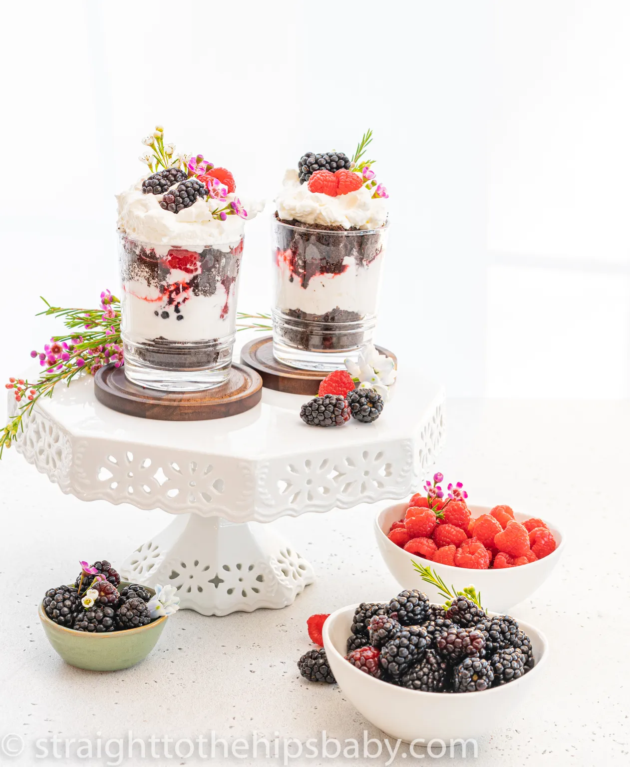 Layered trifles, served with fresh berries on a white cake stand