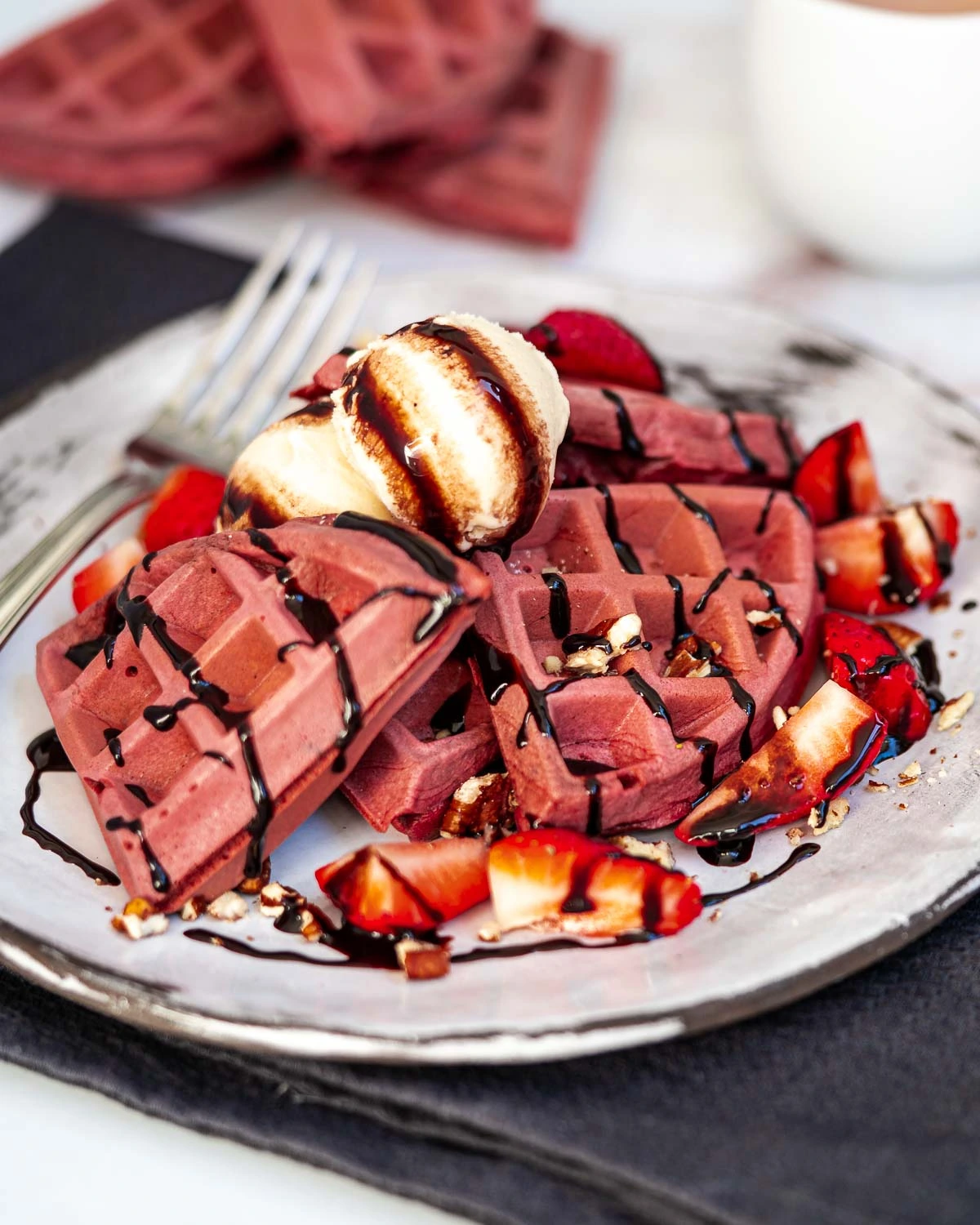 Red velvet waffles, served with ice cream, chocolate and strawberries