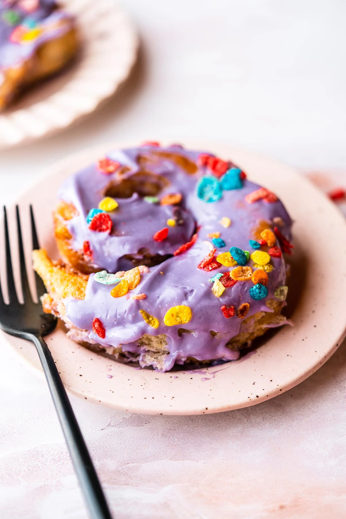 Cinnamon Roll with purple frosting and colorful pebbles, served on a plate