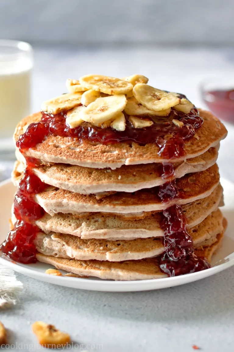 A stack of banana buckwheat pancakes served with jam and bananas