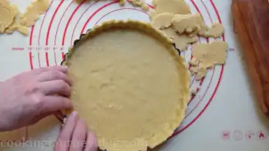 Press the dough to the bottom and sides of the tart pan and cut the edges.