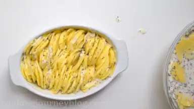 Pick a handful of potato slices and start organizing them into a neat stack in the casserole dish with their edges aligned vertically. Continue placing potatoes in the baking dish, working around the perimeter and into the center until very tightly packed. Do the same in the other baking dish.