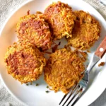Sweet potato fritters with a fork on a white plate