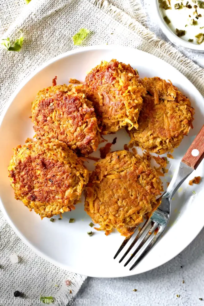 Sweet potato fritters served with a sauce on a white plate