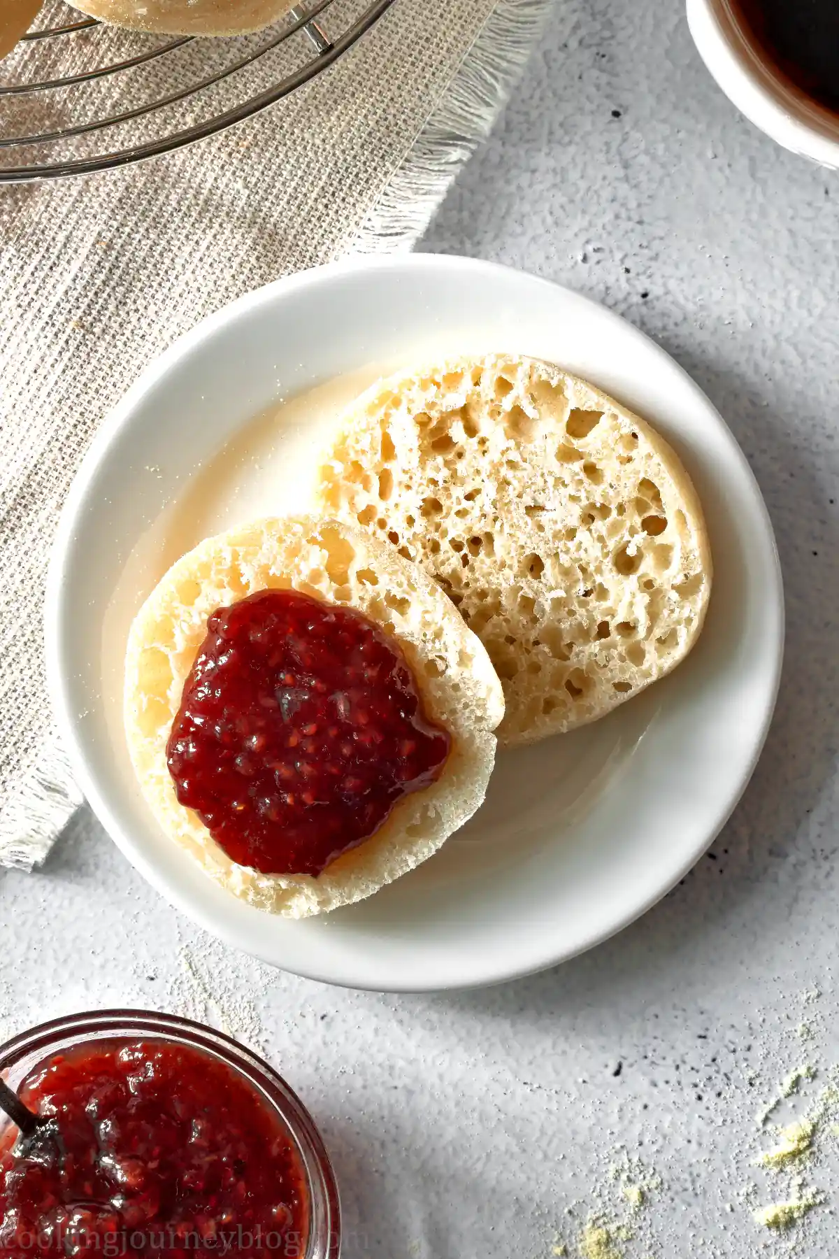 White plate with Vegan English muffins, cut in half and served with strawberry jam